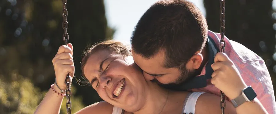 A laughing couple sharing a moment on a swing